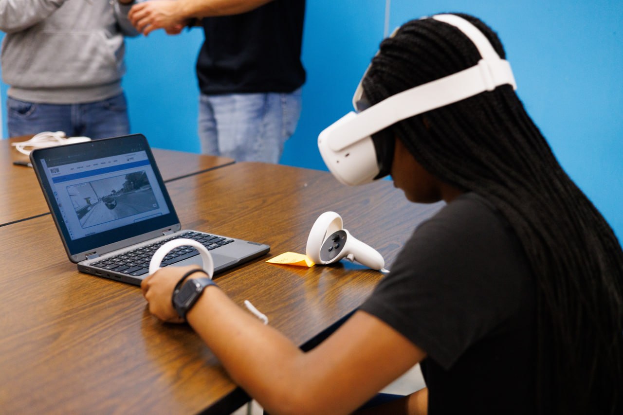 An E4 Youth team member guiding a participant using a virtual reality headset