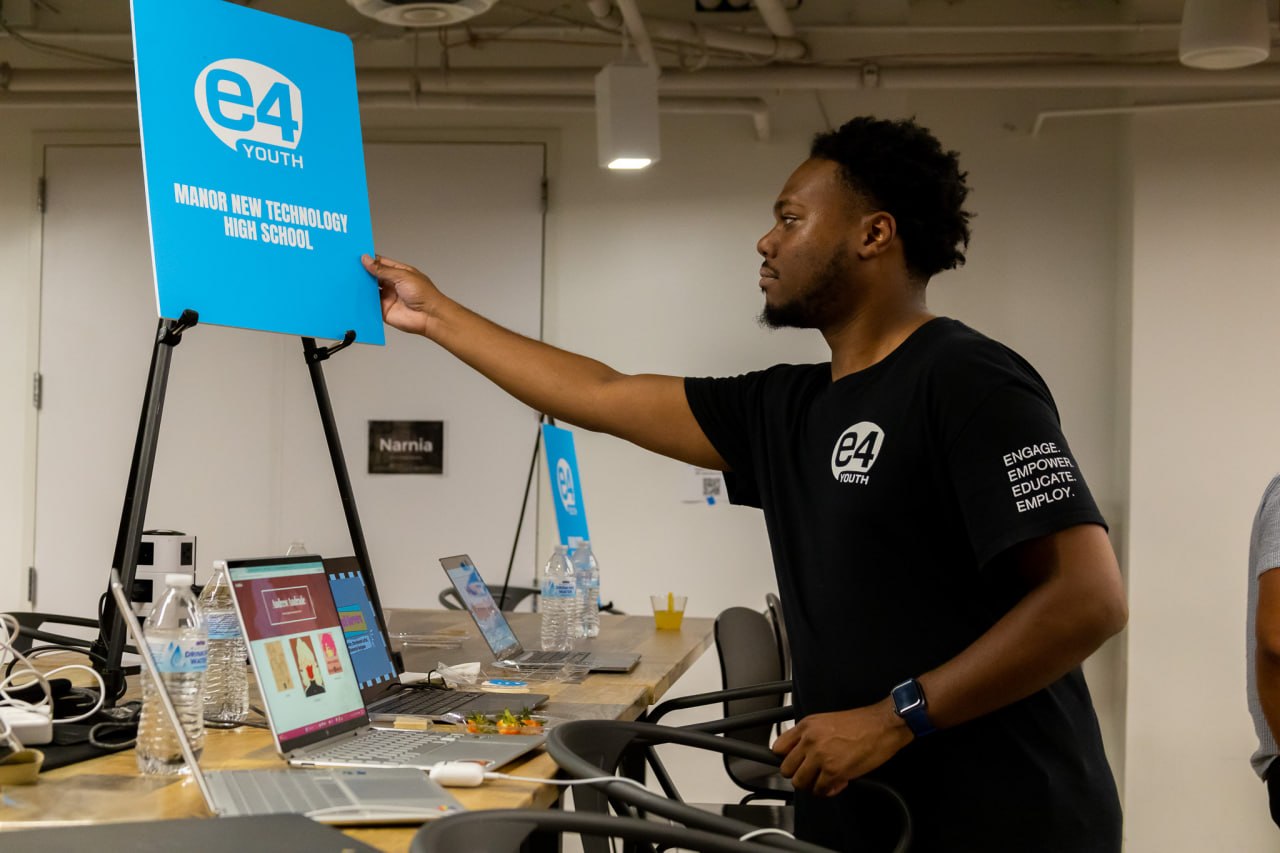An E4 Youth team member prepares a student technology showcase