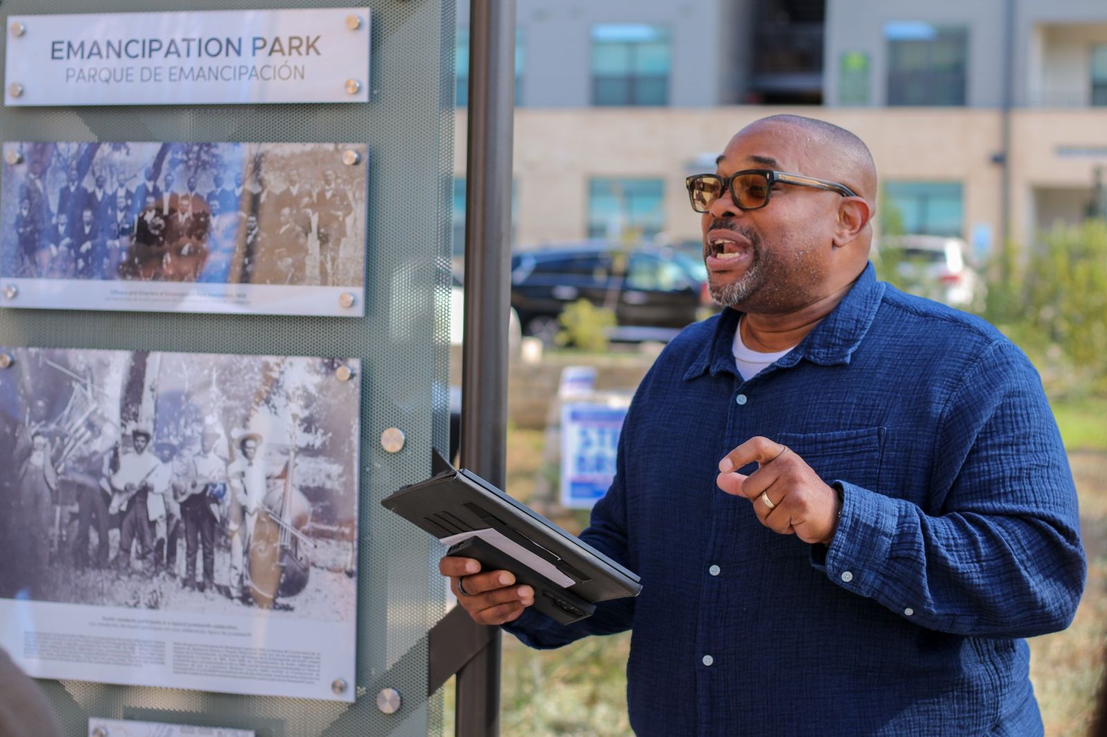 A speaker stands beside the Emancipation Park historical marker near the WOW Heritage Center